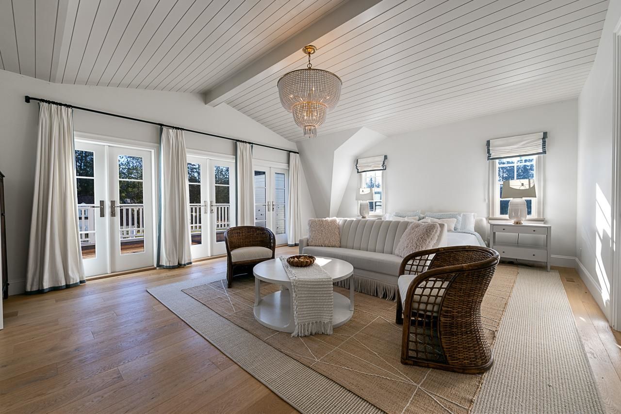Grace Acres primary suite sitting area — gambrel ceiling, crystal chandelier, French doors to private balcony