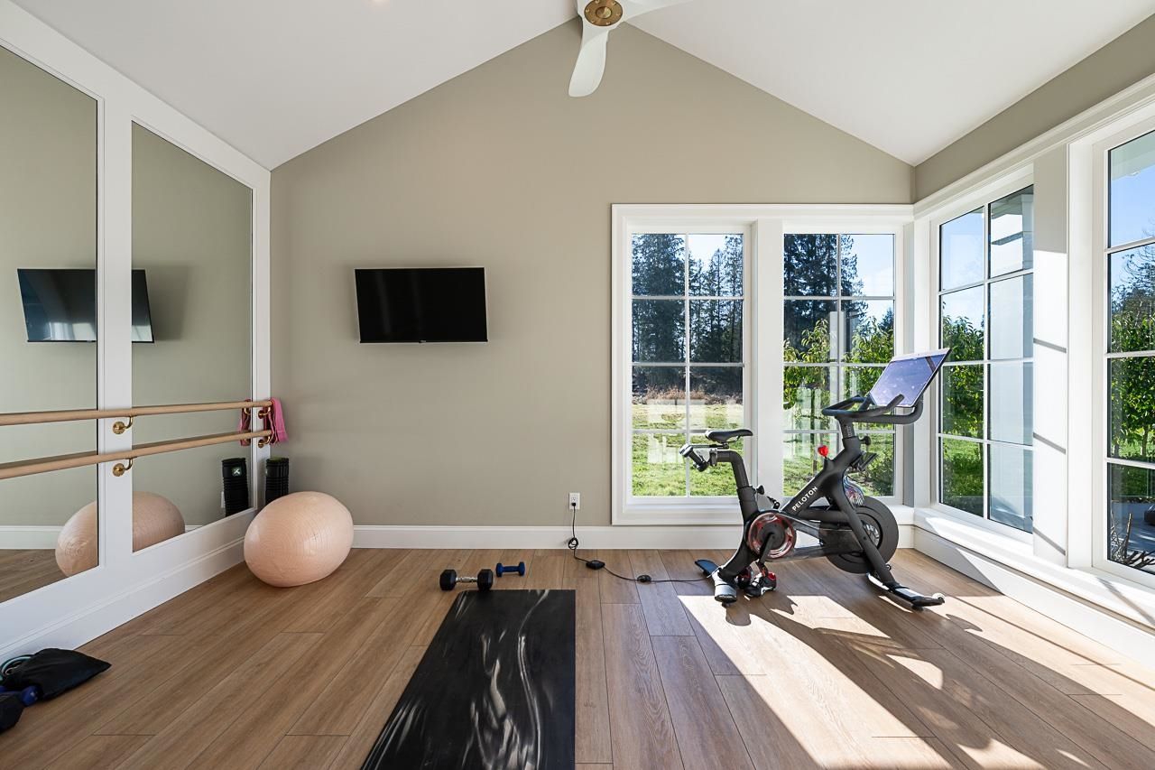 Grace Acres home gym — ballet barre, Peloton, French doors to grounds, vaulted ceiling