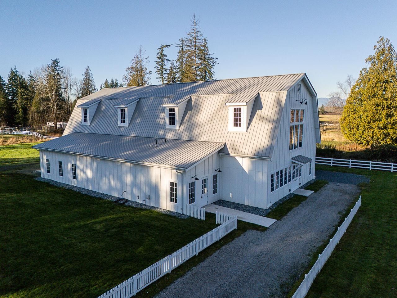 Grace Acres barn exterior — white board and batten, standing seam metal roof, gambrel profile matching main house