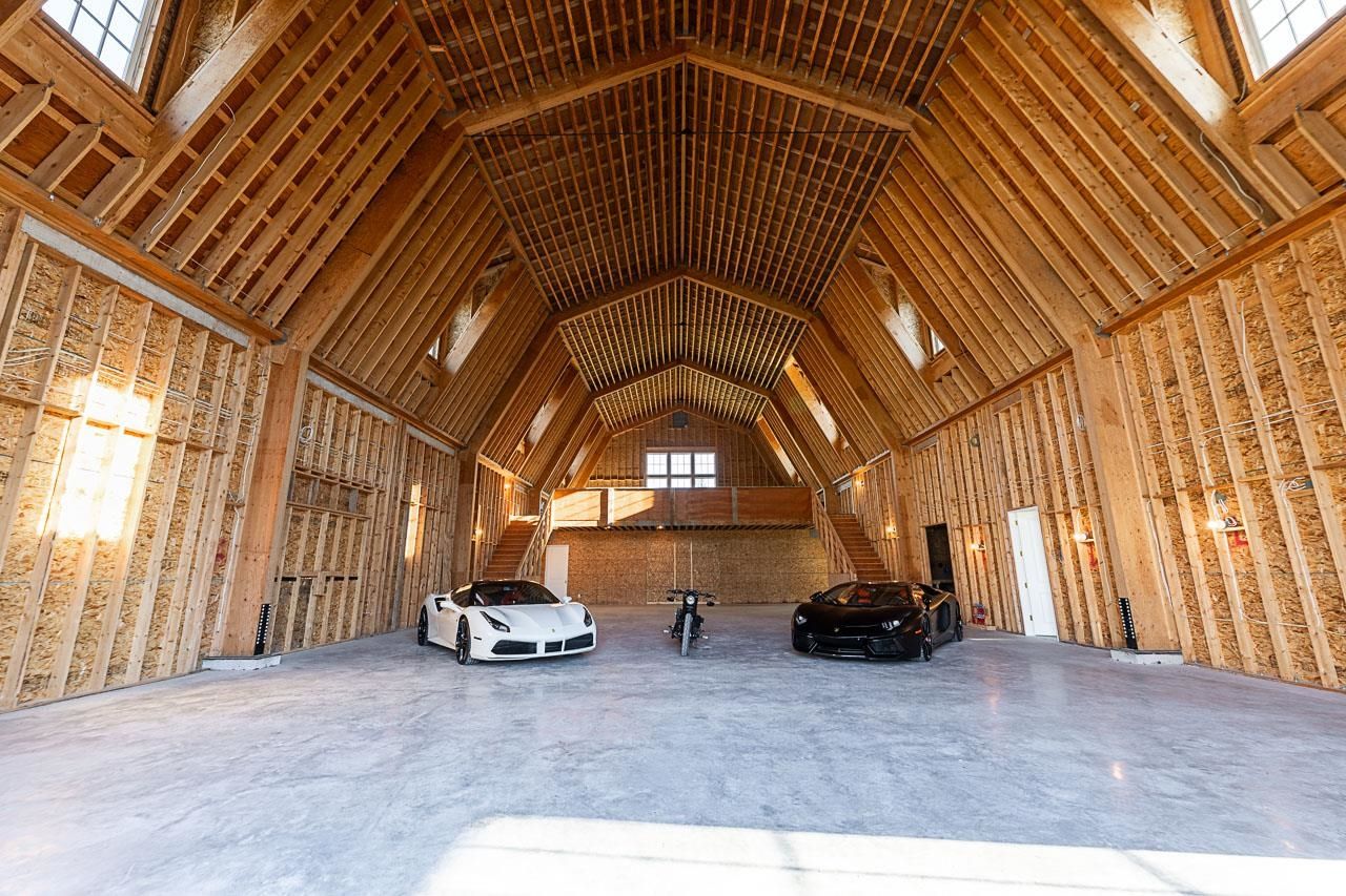 Grace Acres barn interior — clear span timber cathedral ceiling, Ferrari and Lamborghini, upper loft