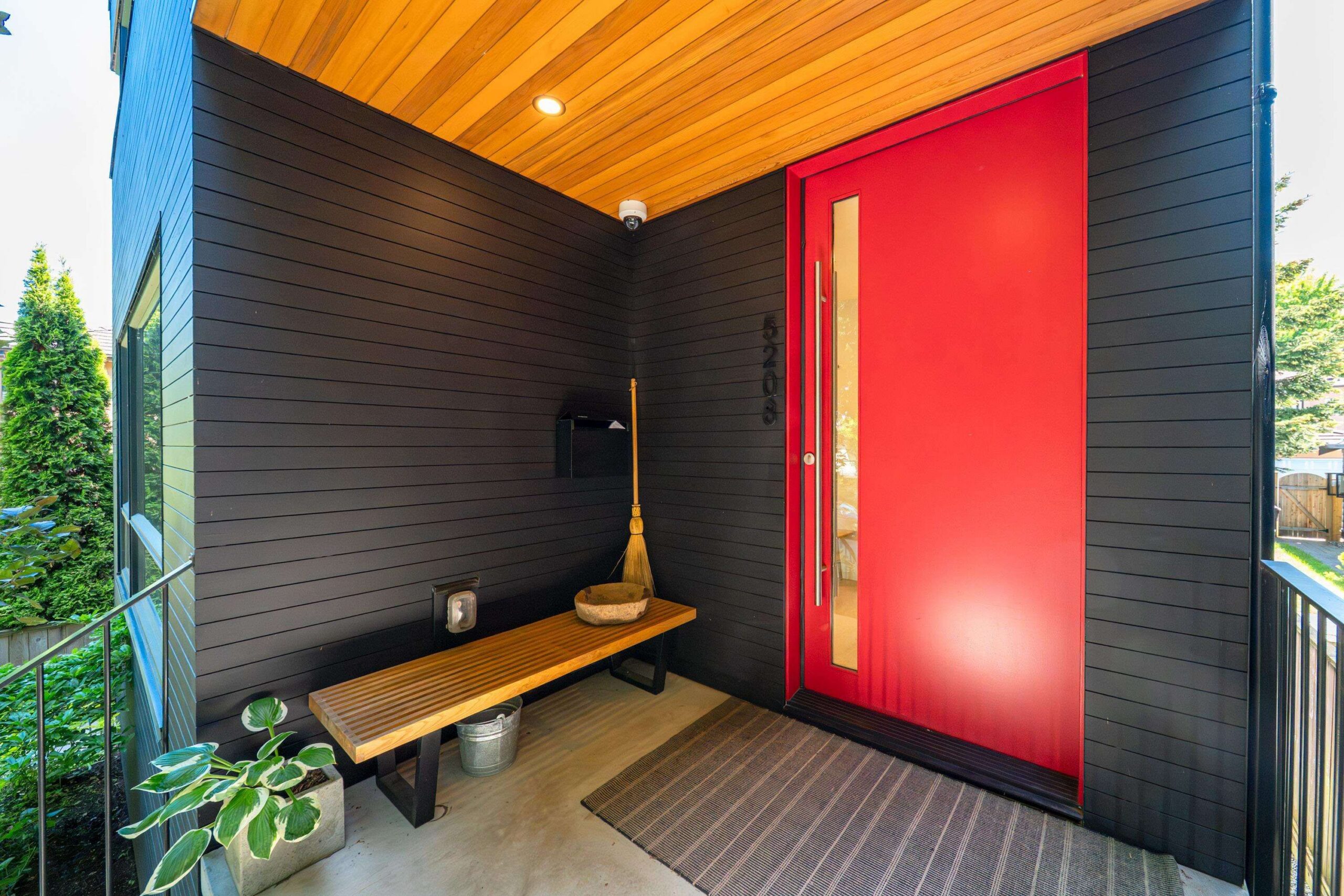 Close-up of the front door area at 5208 Ross Street showing the wood and black exterior cladding detail