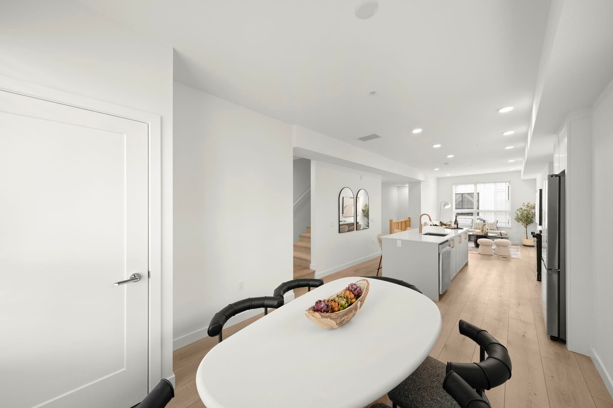 Dining area at 6-728 Lea Avenue with white oval table, black leather chairs, and a view through to the kitchen