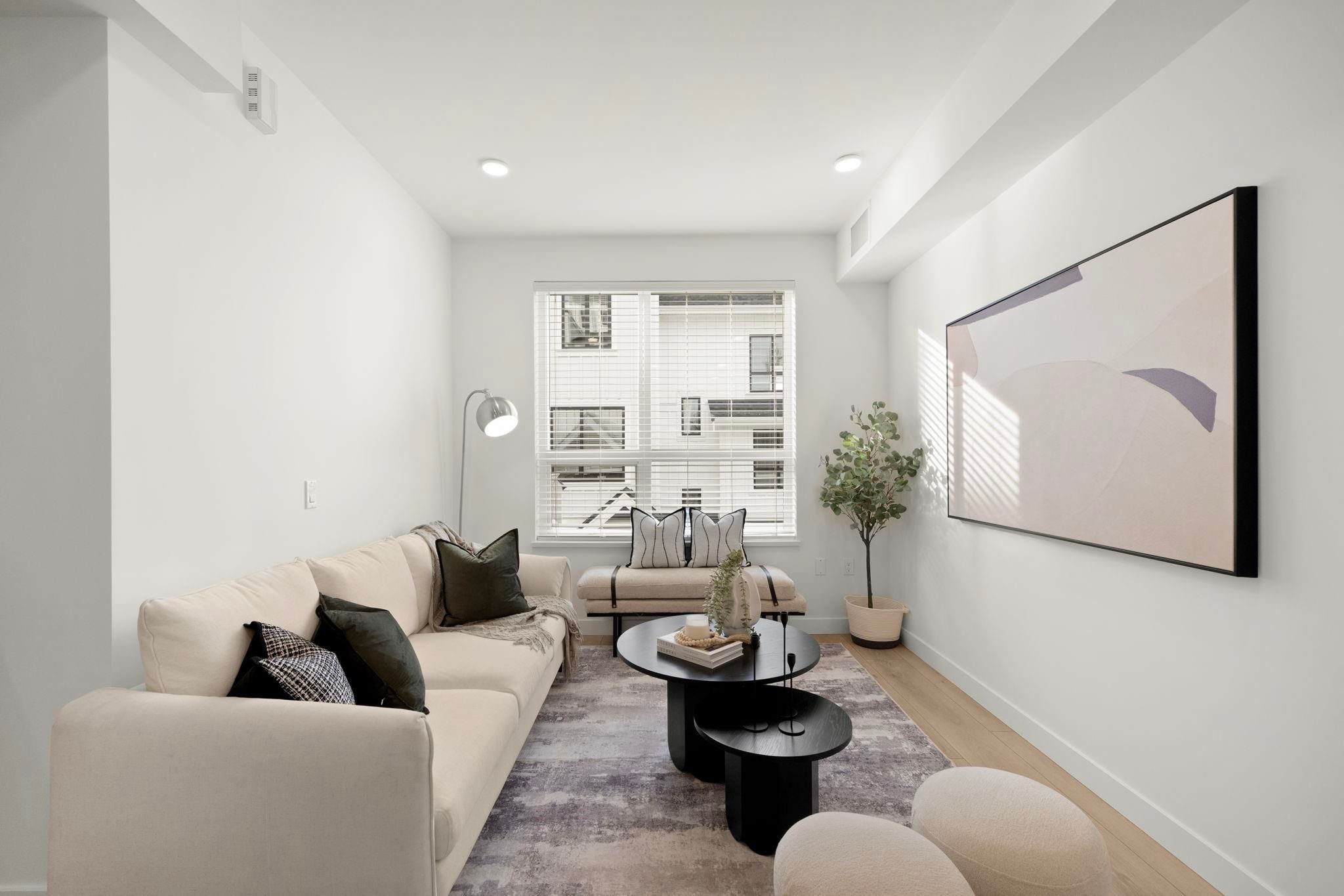 Living room at 6-728 Lea Avenue with cream sectional, black coffee tables, and abstract framed art