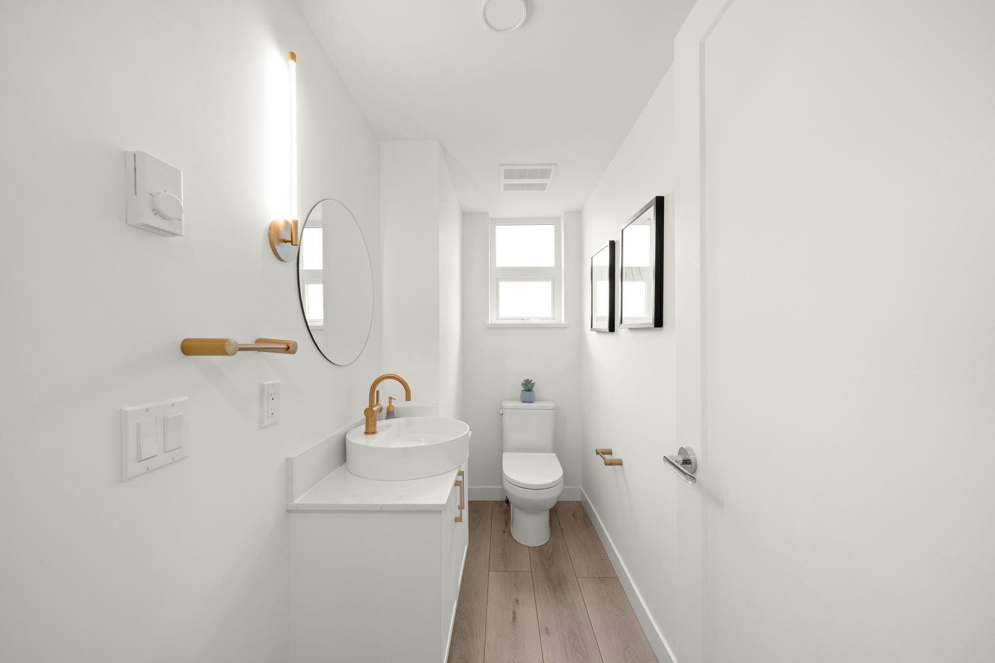 Main floor powder room at 6-728 Lea Avenue with round vessel sink, brass fixtures, and wood-look flooring
