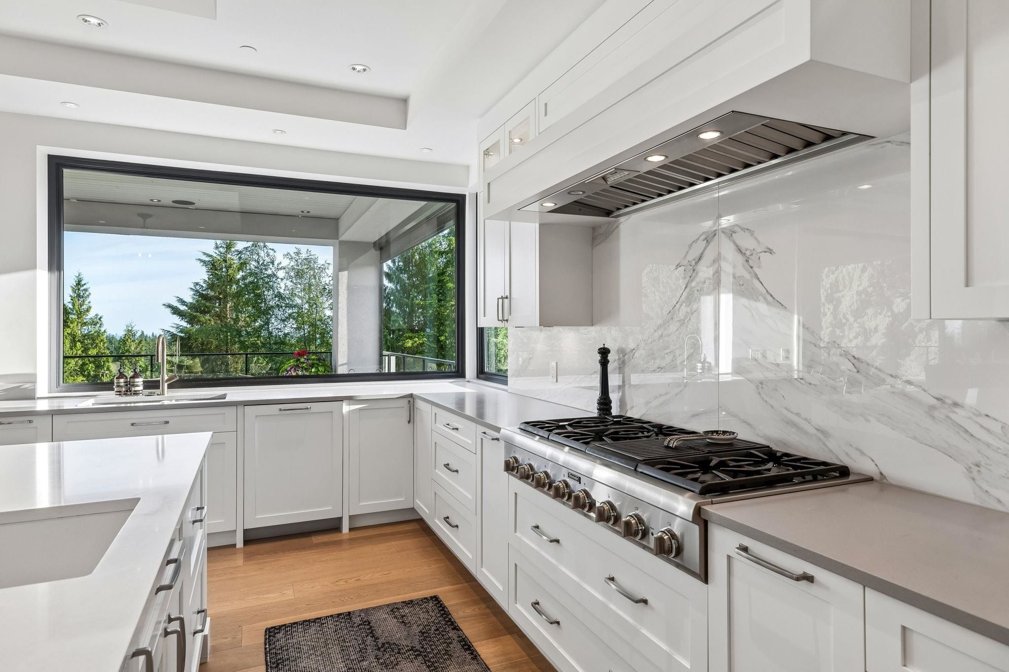 Chef's kitchen with 10-foot island and Thermador appliances opening to covered patio at Anmore estate