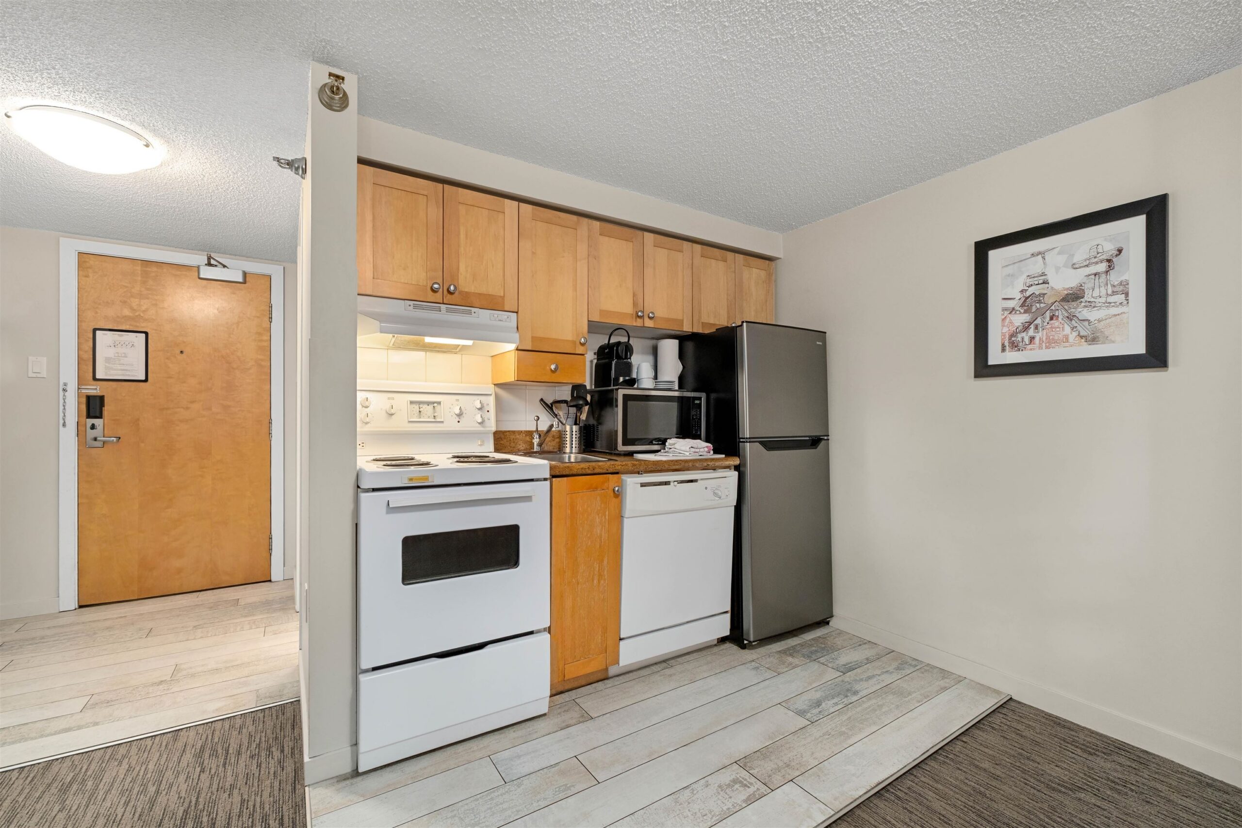Kitchen at Whistler Village Inn & Suites — full-size range, stainless fridge, dishwasher, microwave in a compact layout