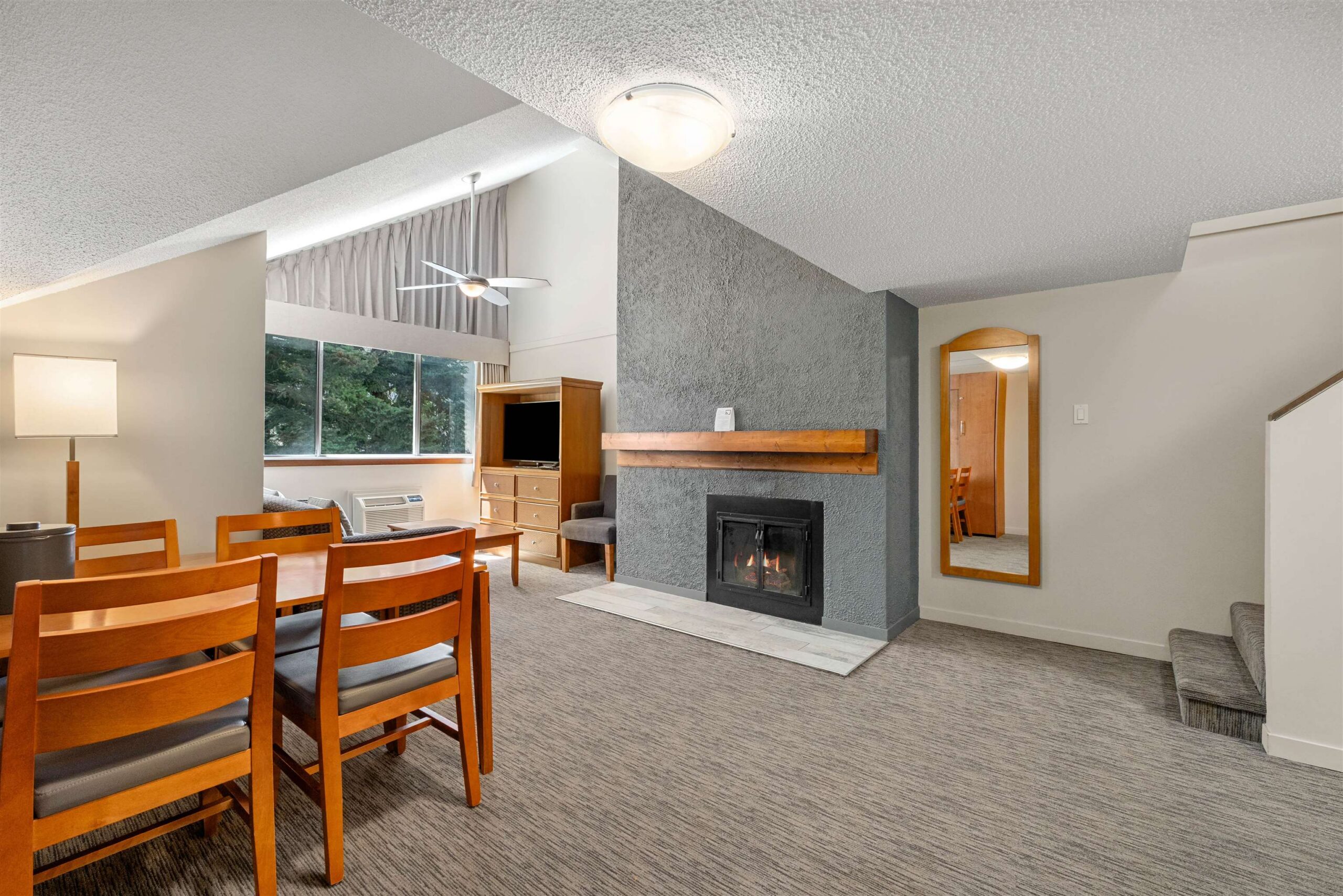 Living/dining area at Whistler Village Inn & Suites with gas fireplace, vaulted ceiling, and mountain-lodge finishes