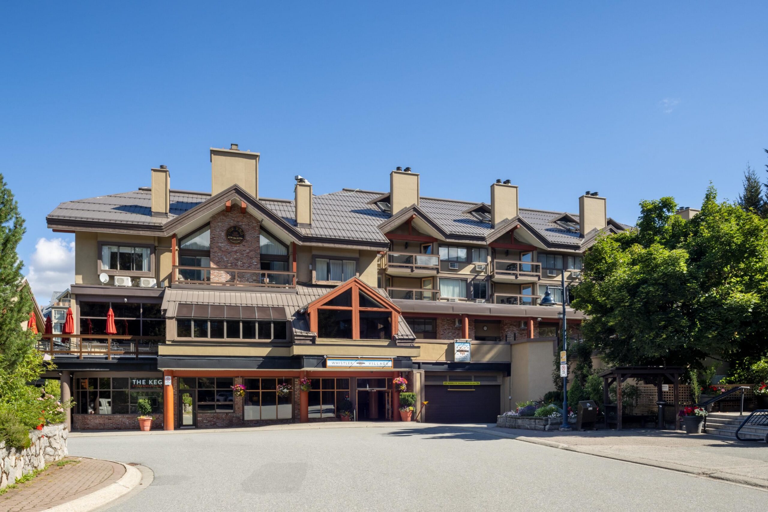 Exterior of Whistler Village Inn & Suites at 4429 Sundial Place, Whistler Village — three-storey mountain-lodge building with covered balconies and ground-floor retail