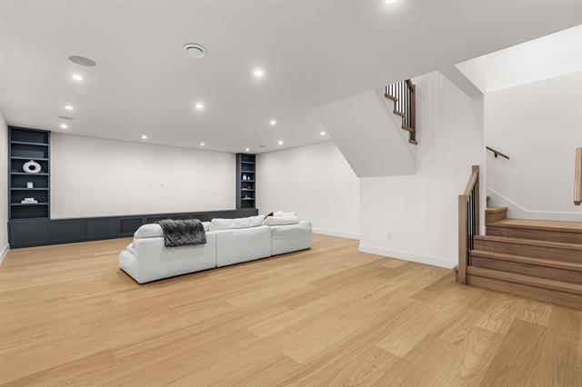 Open recreation room with built-in shelving at Glenayre new-construction home, ready for a home theatre or golf simulator