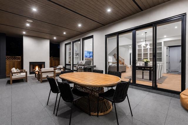 Covered patio with fireplace and outdoor dining at 944 Caithness Crescent, Glenayre