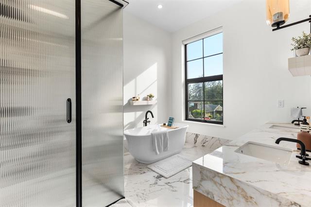 Primary ensuite with freestanding soaker tub and glass shower at Glenayre new-construction home