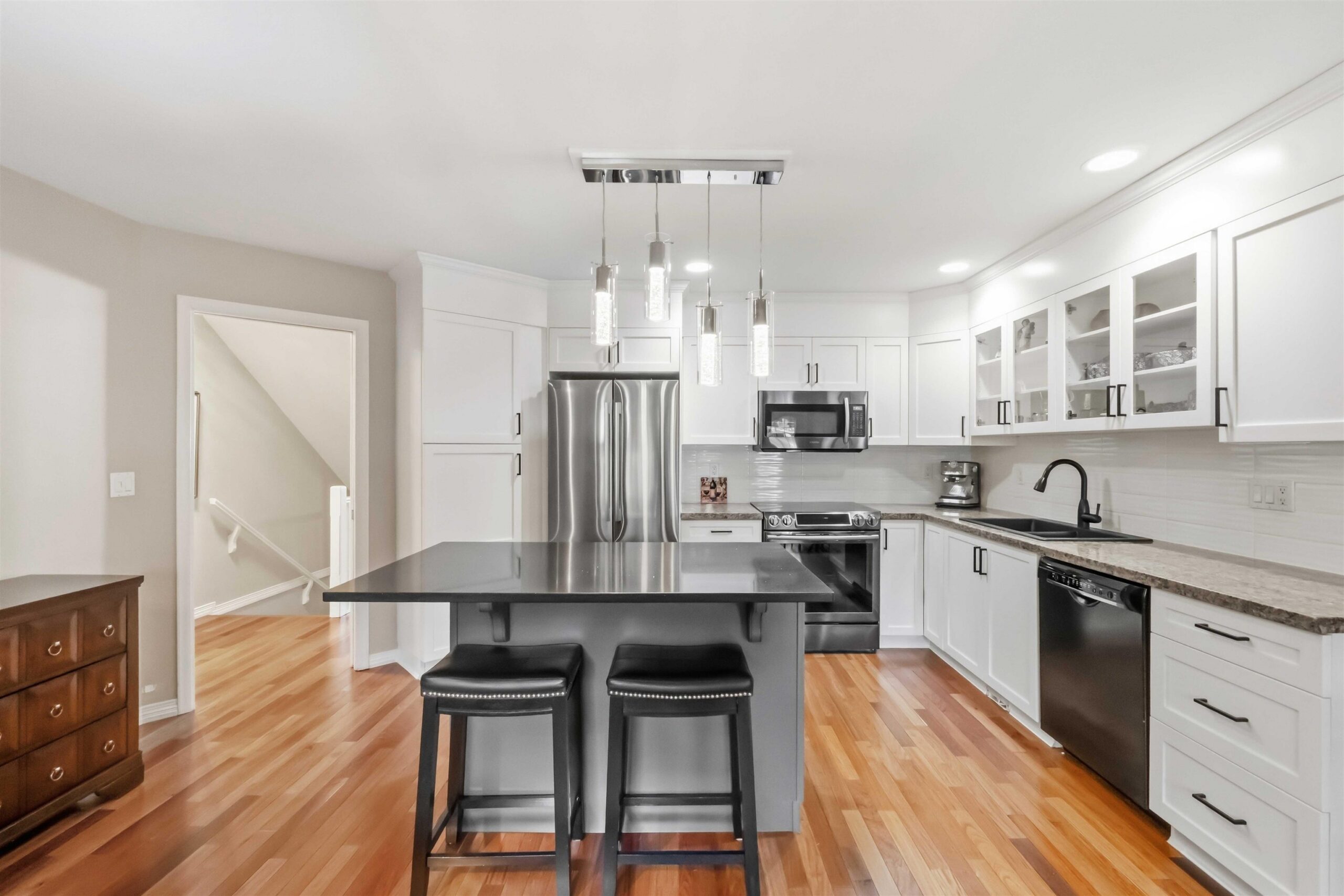 Renovated kitchen with island, stainless appliances, and white cabinetry in 3-16995 64th Avenue, Cloverdale