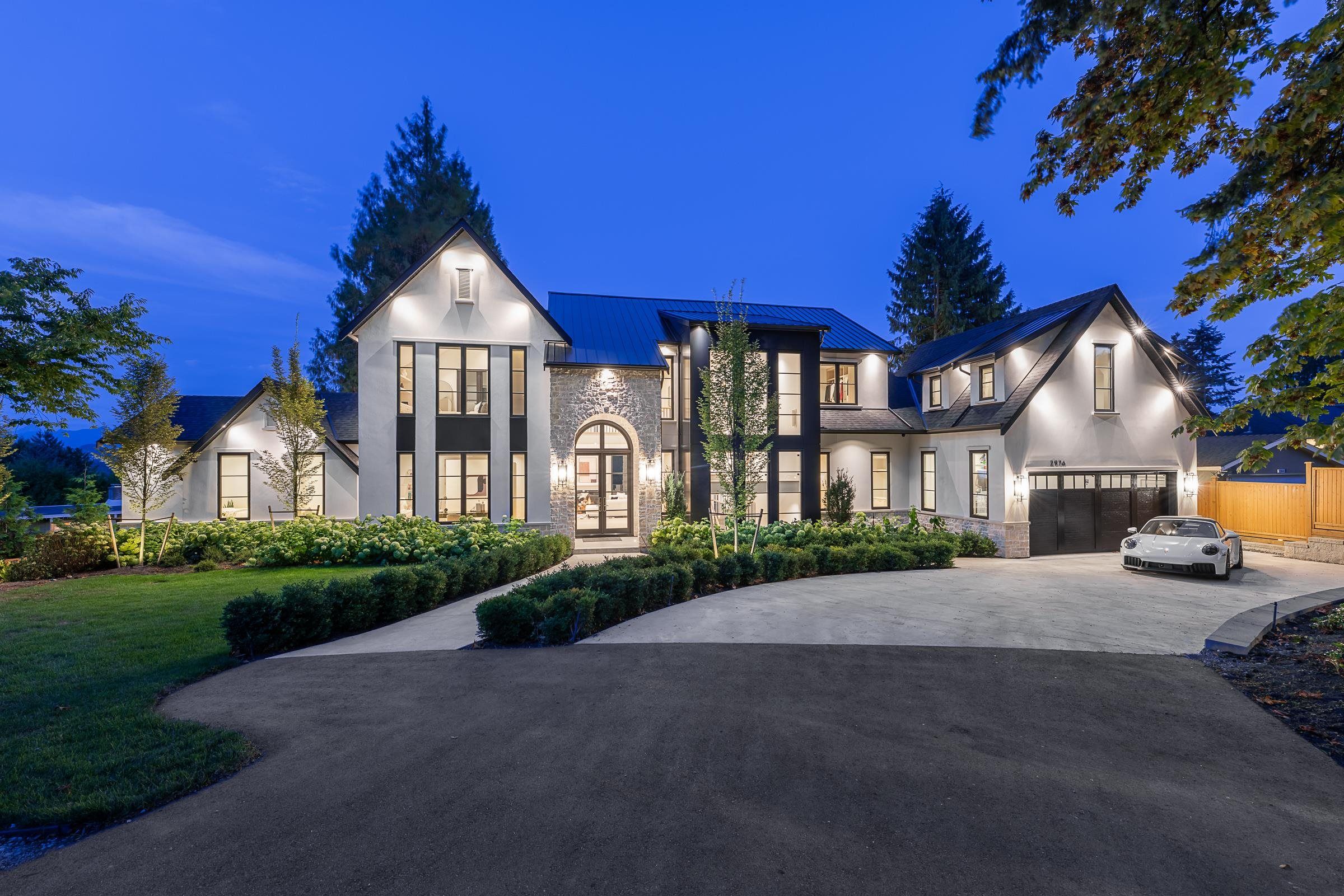 Twilight exterior of a custom two-storey home with stone and black steel accents at 2976 Lazy A Street in Ranch Park, Coquitlam