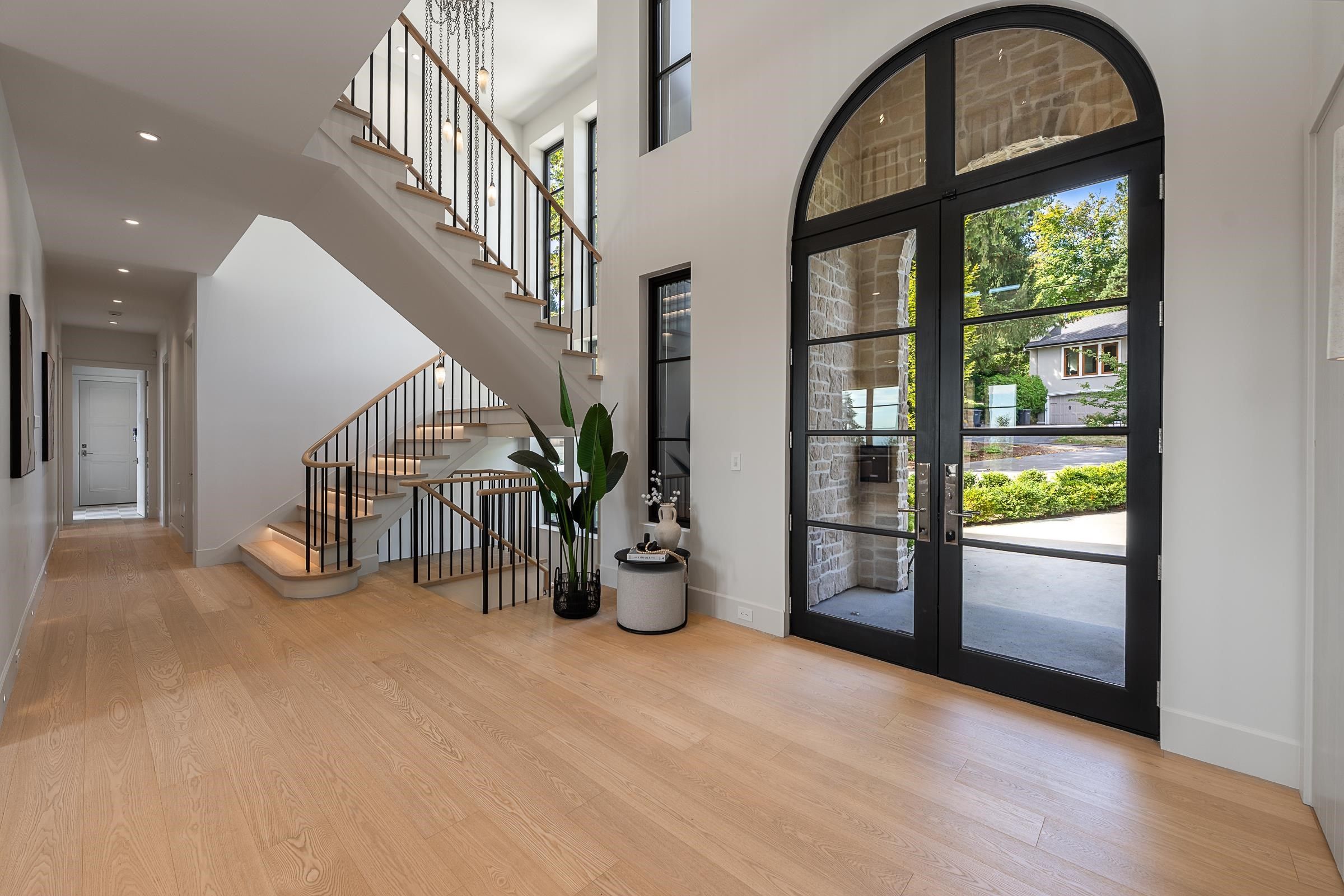 Arched black steel and glass front entry with curved floating staircase at 2976 Lazy A Street, Ranch Park