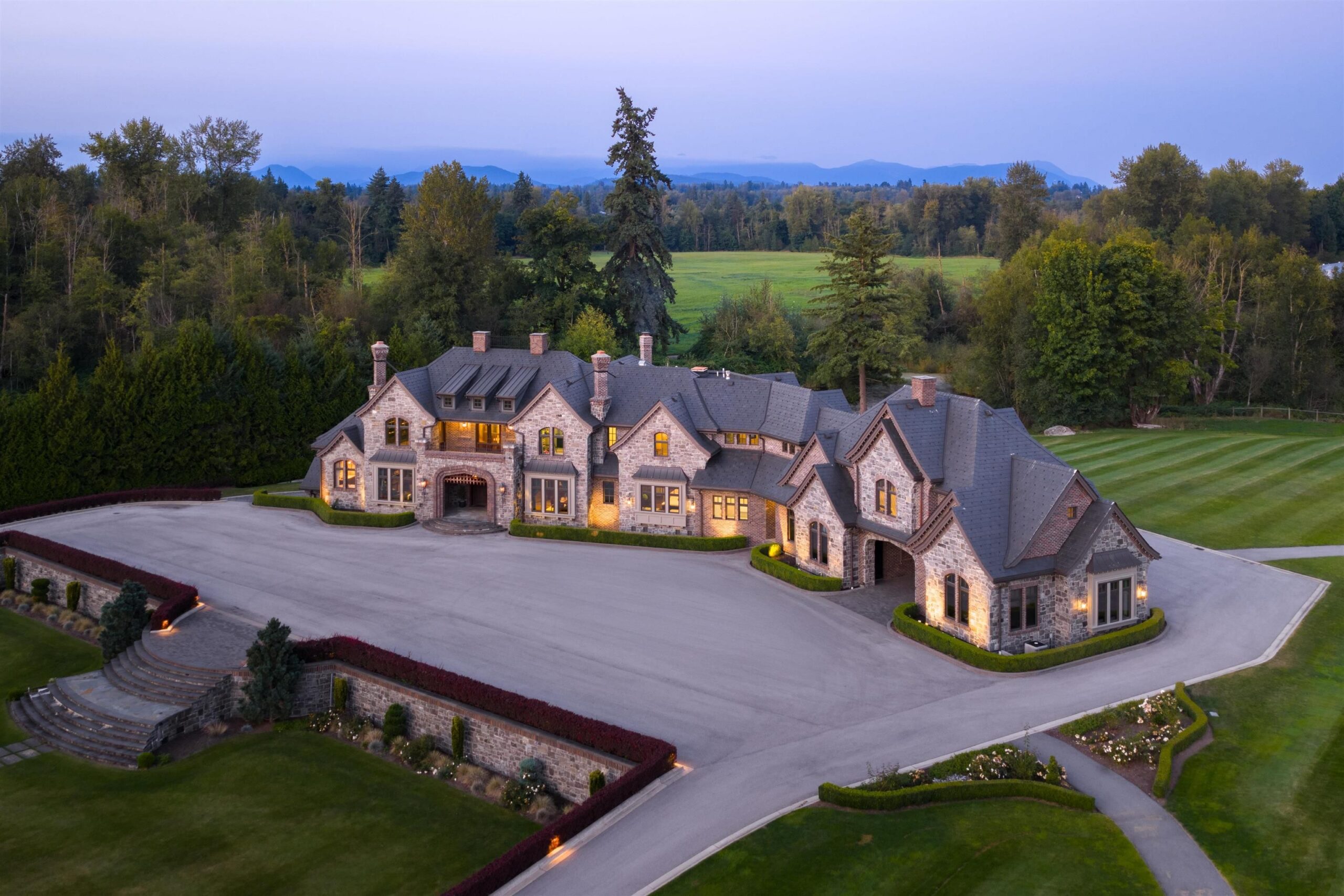 Aerial view of Tannin Manor at dusk, a stone-clad estate on 28.75 acres in Glen Valley, Langley BC